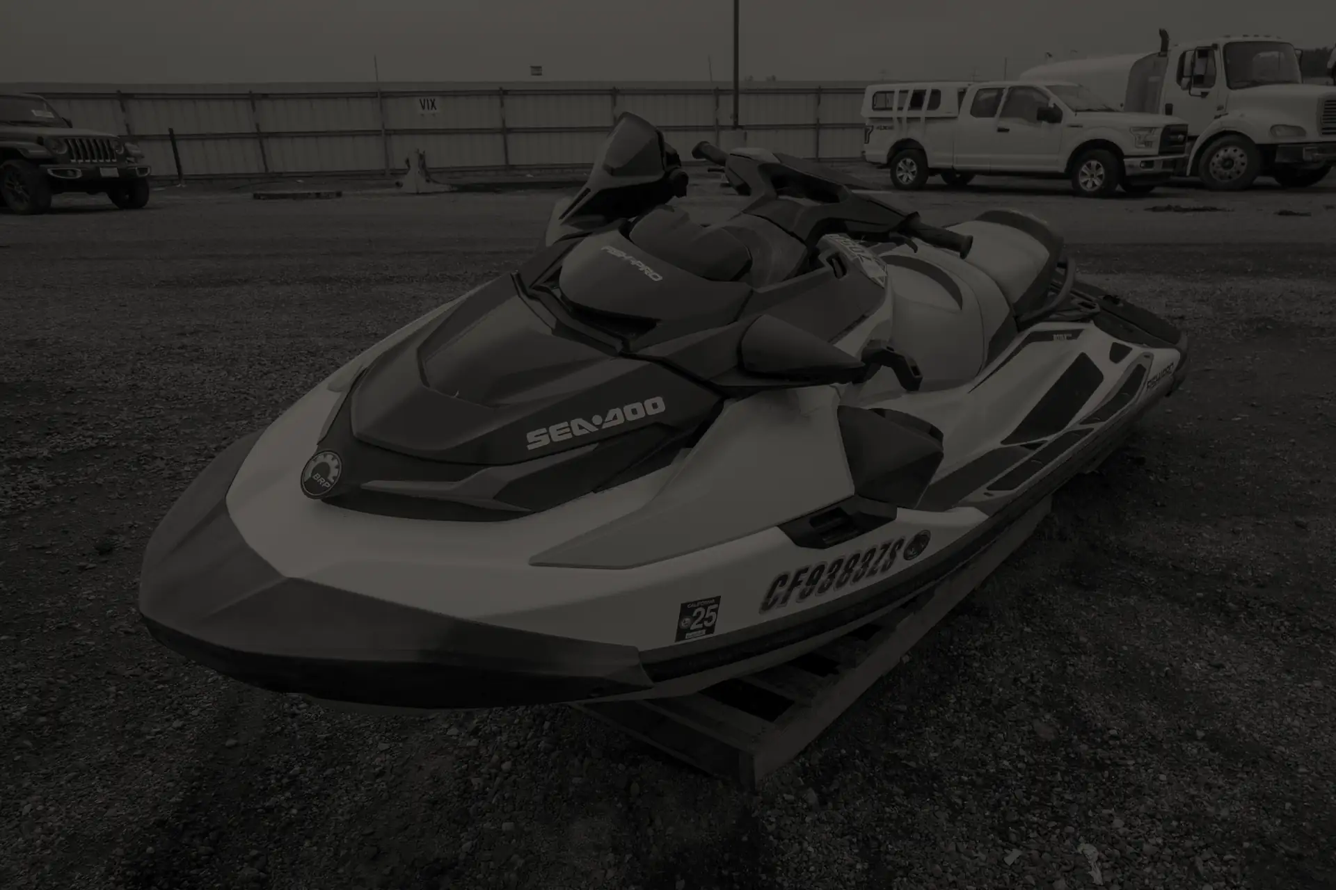 White and black crashed Sea-Doo personal watercraft on a wooden pallet in a gravel lot.