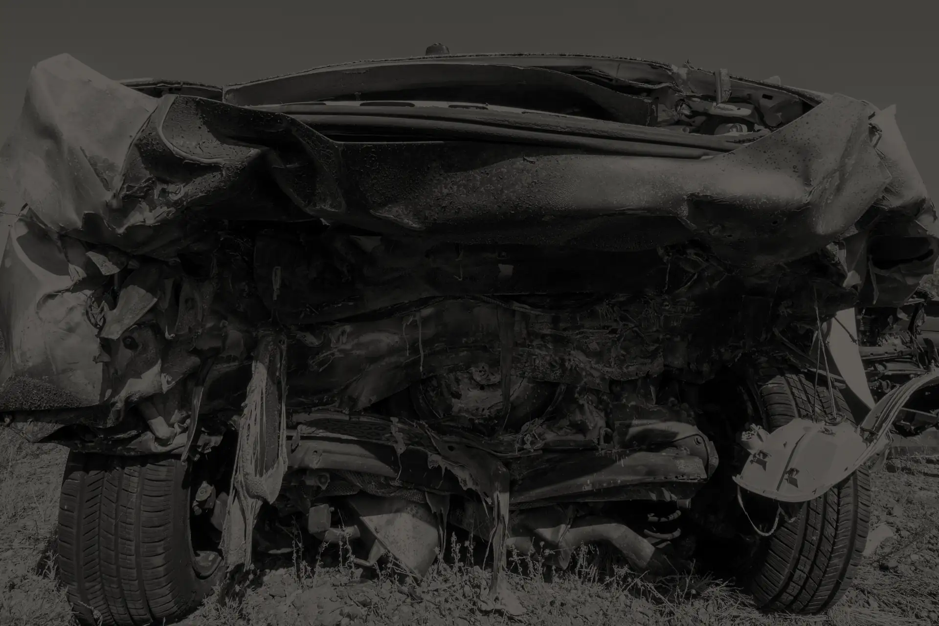 Rear view of a heavily fire-damaged car with melted and warped metal parts.
