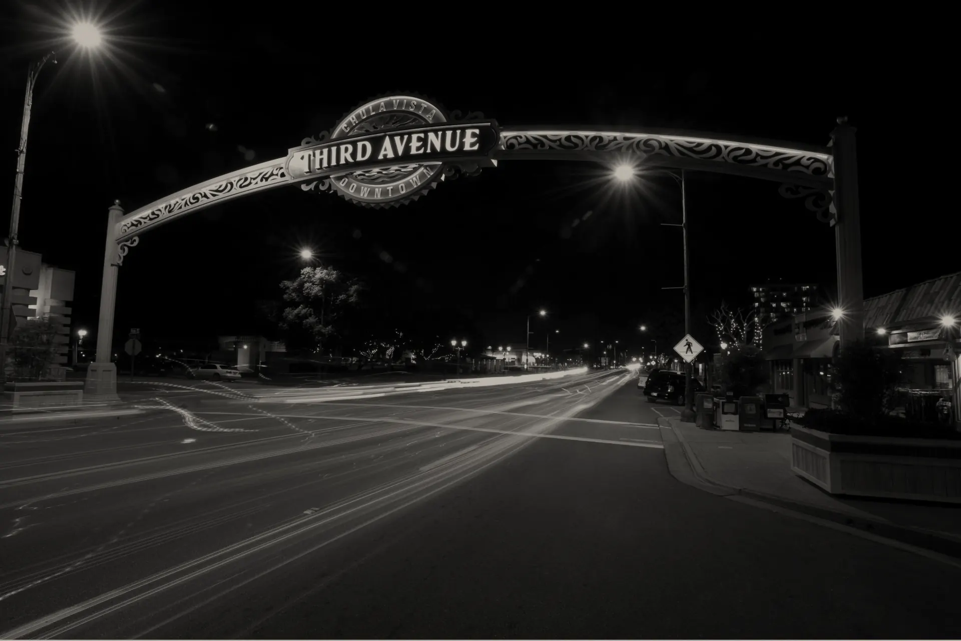 Night view of Third Avenue arch in Chula Vista with light trails from passing cars on the street below.
