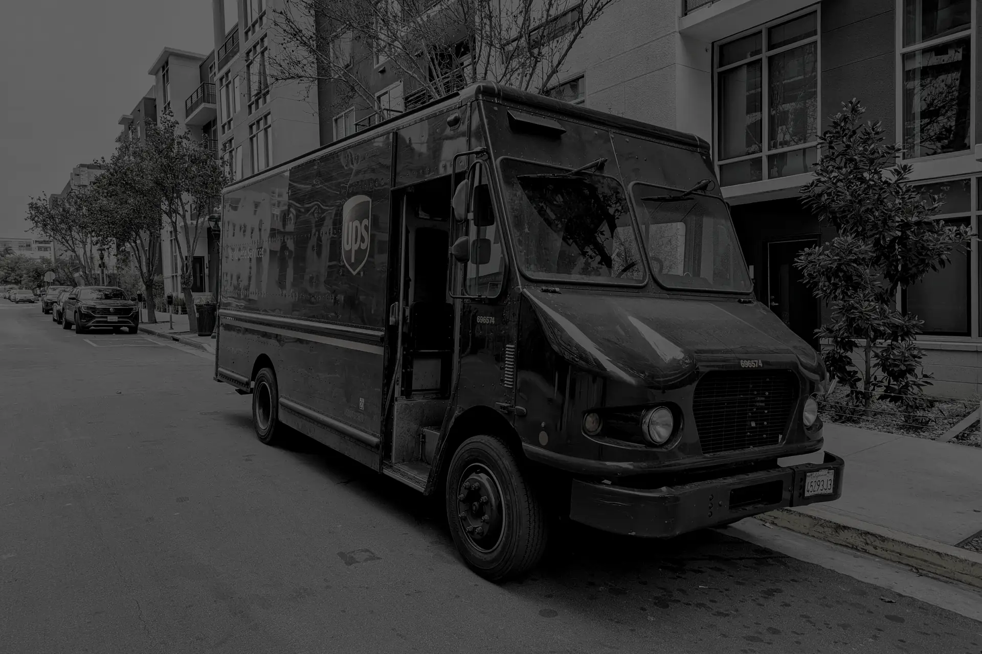 UPS delivery truck parked on downtown city street in San Diego in front of apartment buildings with trees lining the sidewalk.