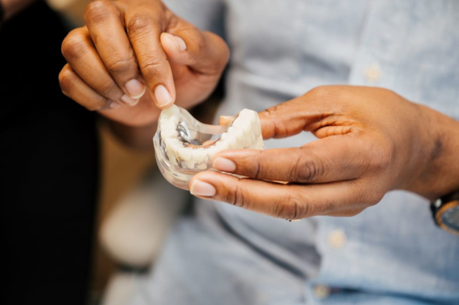 Dentist showing dental implant model to patient during consultation.