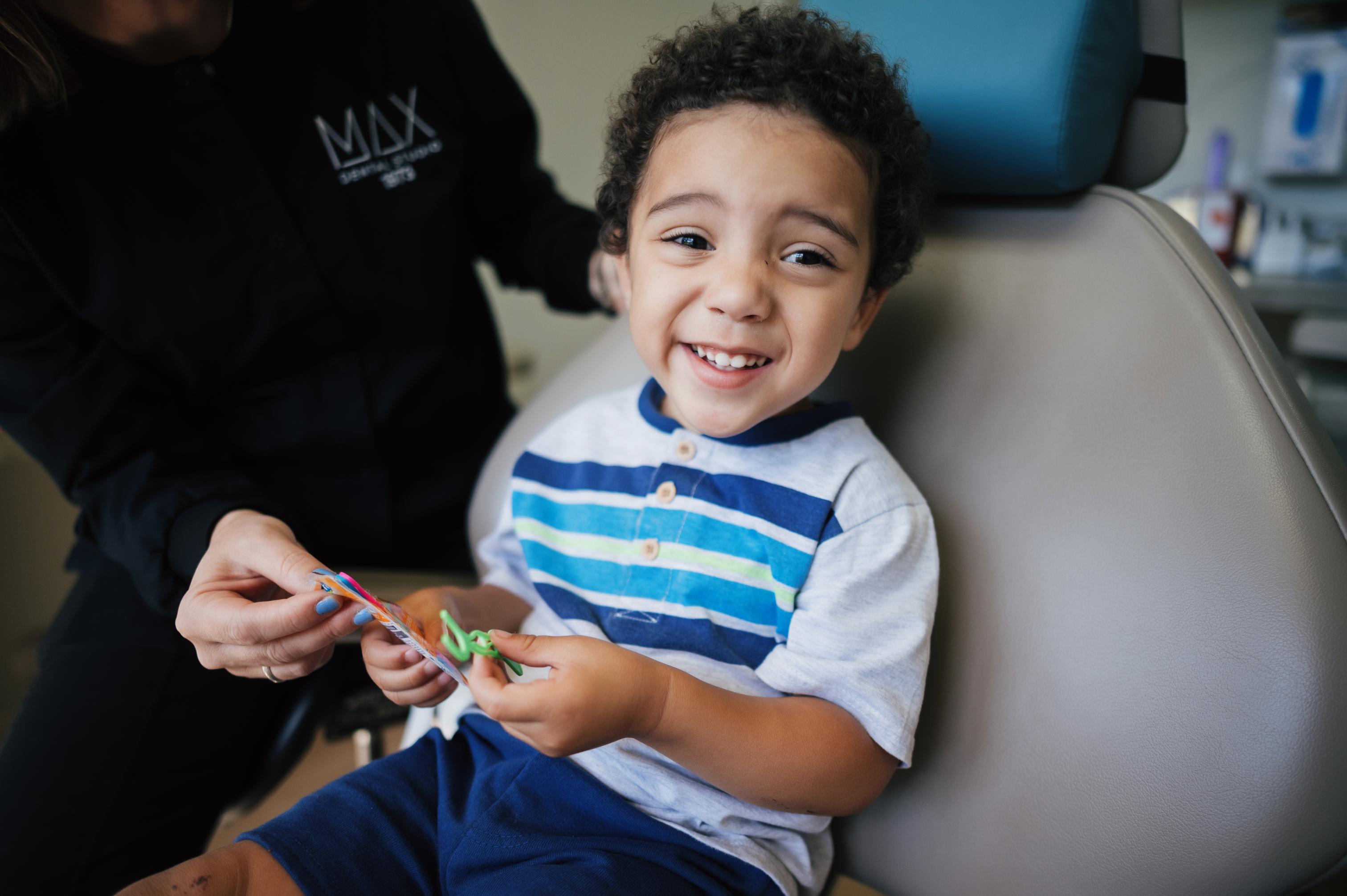 Young boy smiling in dental chair after a successful pediatric dental visit.