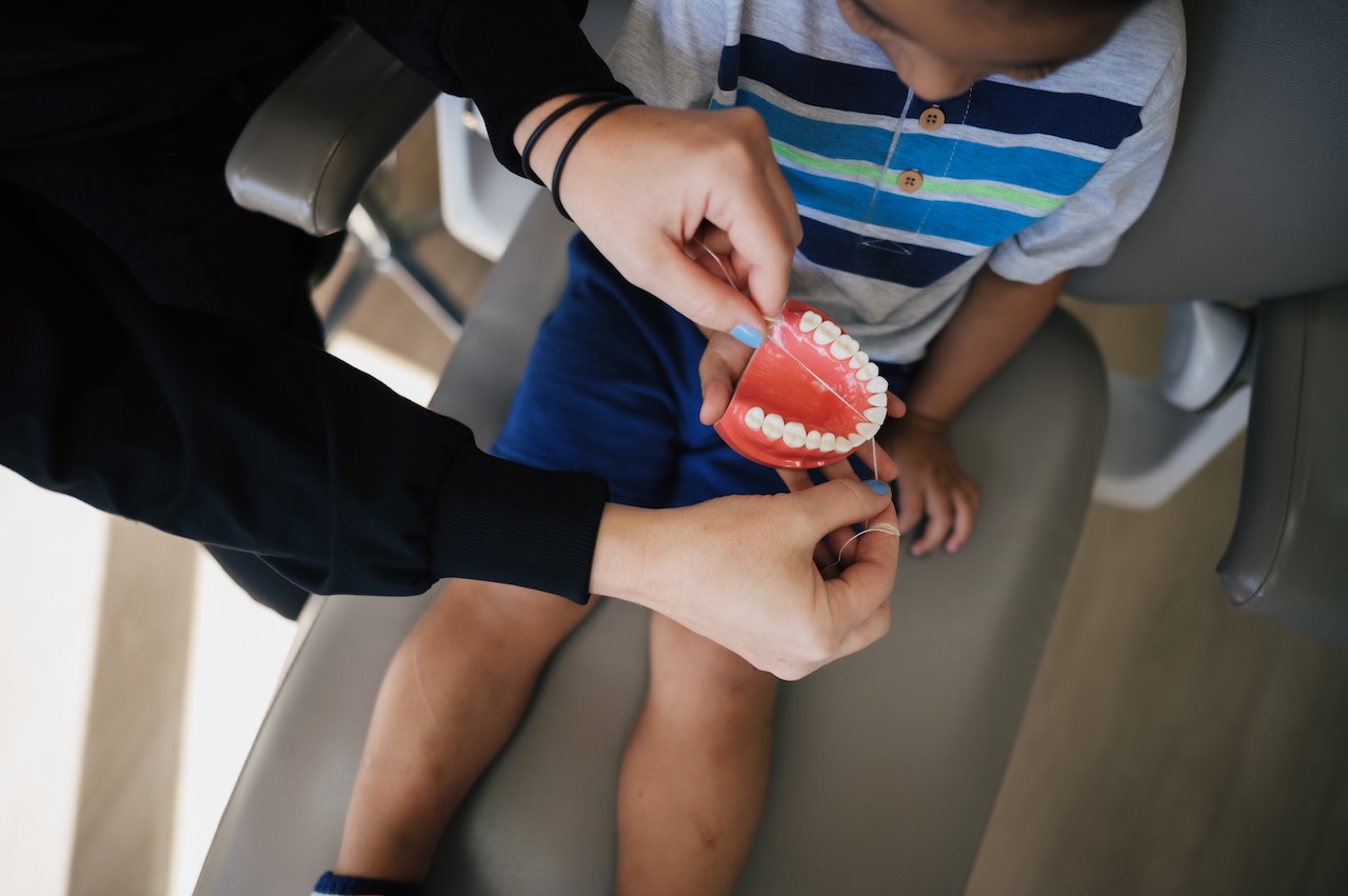 Dentist showing a child the color of a tooth at Max Dental Studio. 
