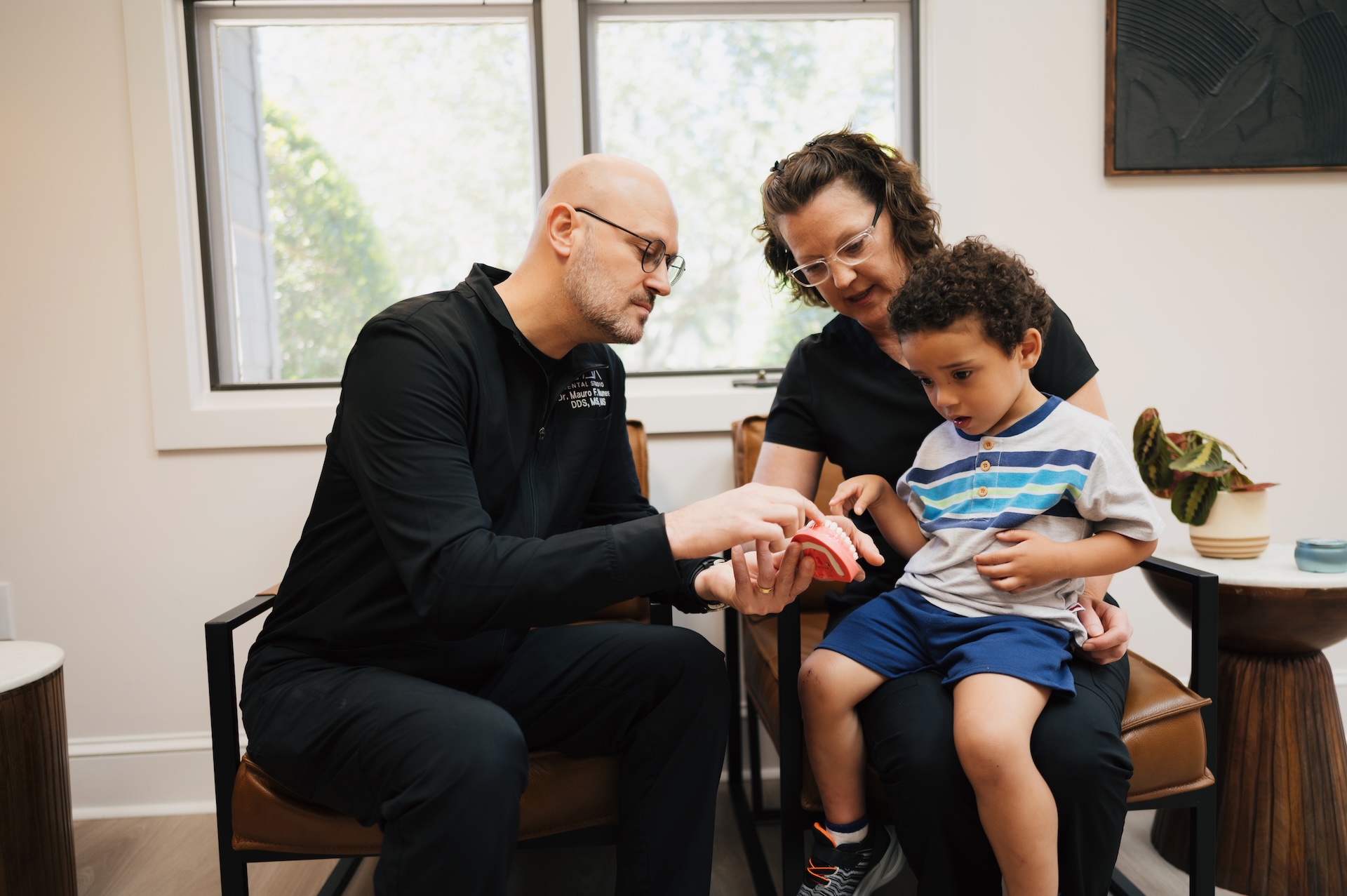 Doctor at Max Dental Studio showing a kid a teeth model to talk him bout the procedure and aftercare