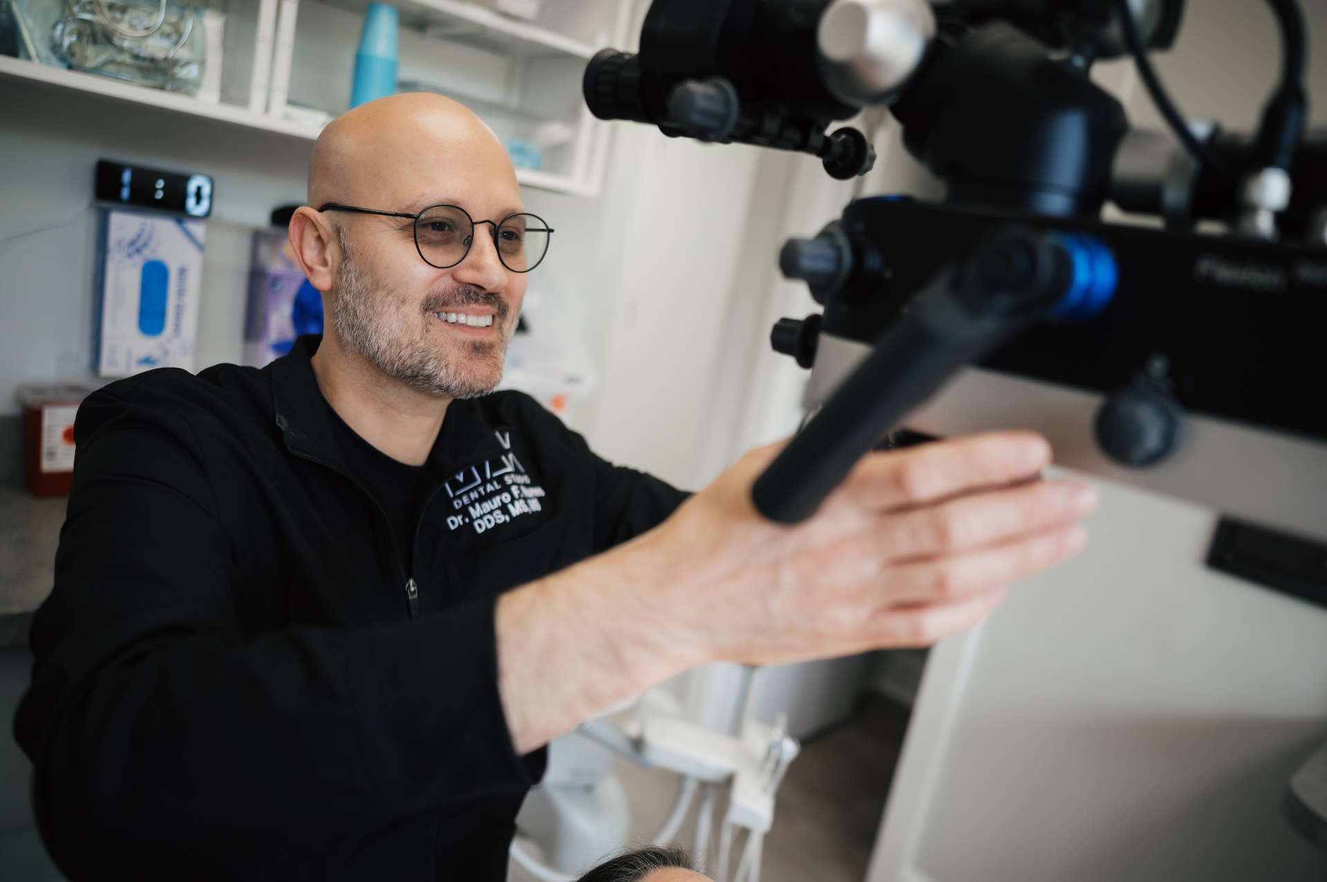 `Dr. Mauro Flamini DDS smiling while positioning dental operating microscope at Max Dental Studio`