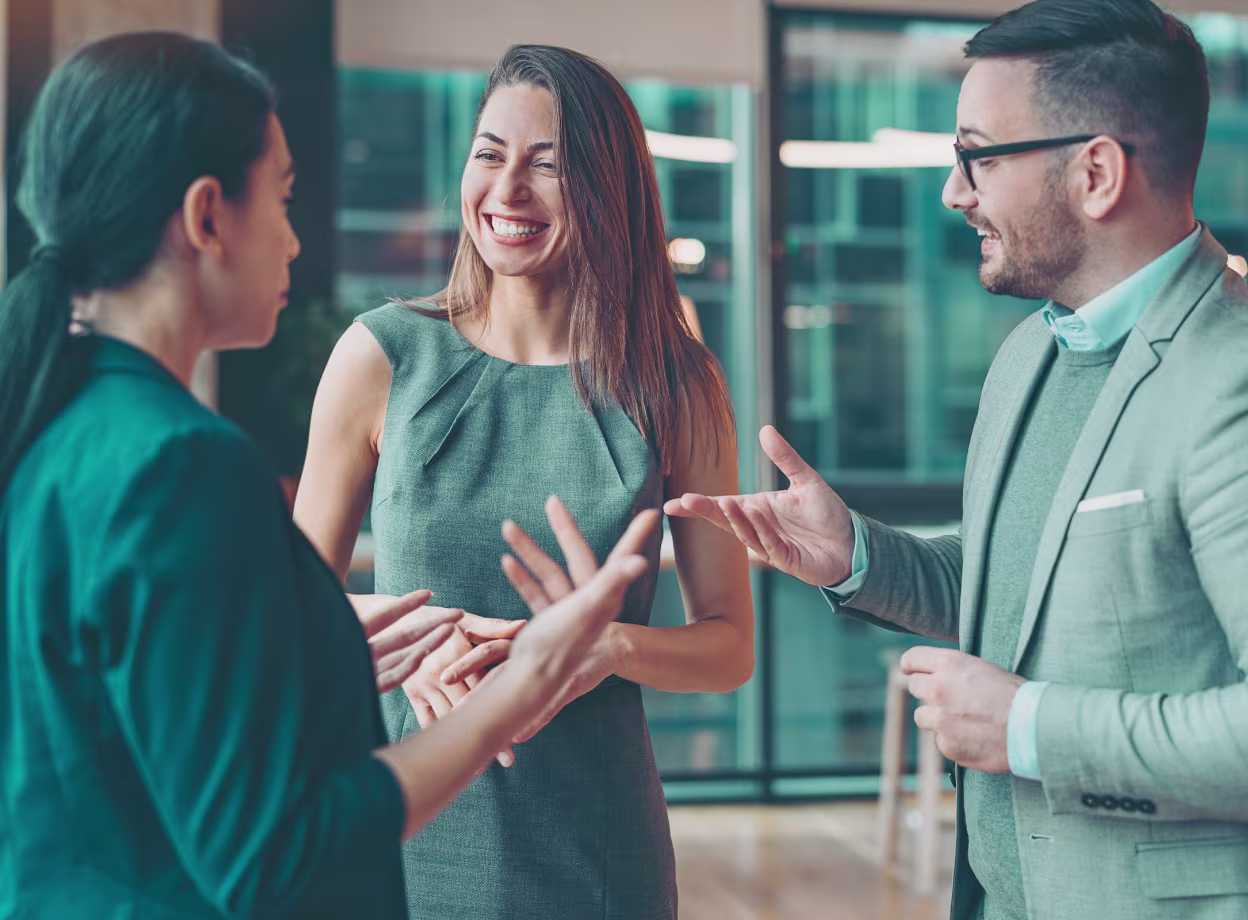 Führungsstile im modernen Unternehmen: Drei Führungskräfte im Gespräch in einem modernen Büro.