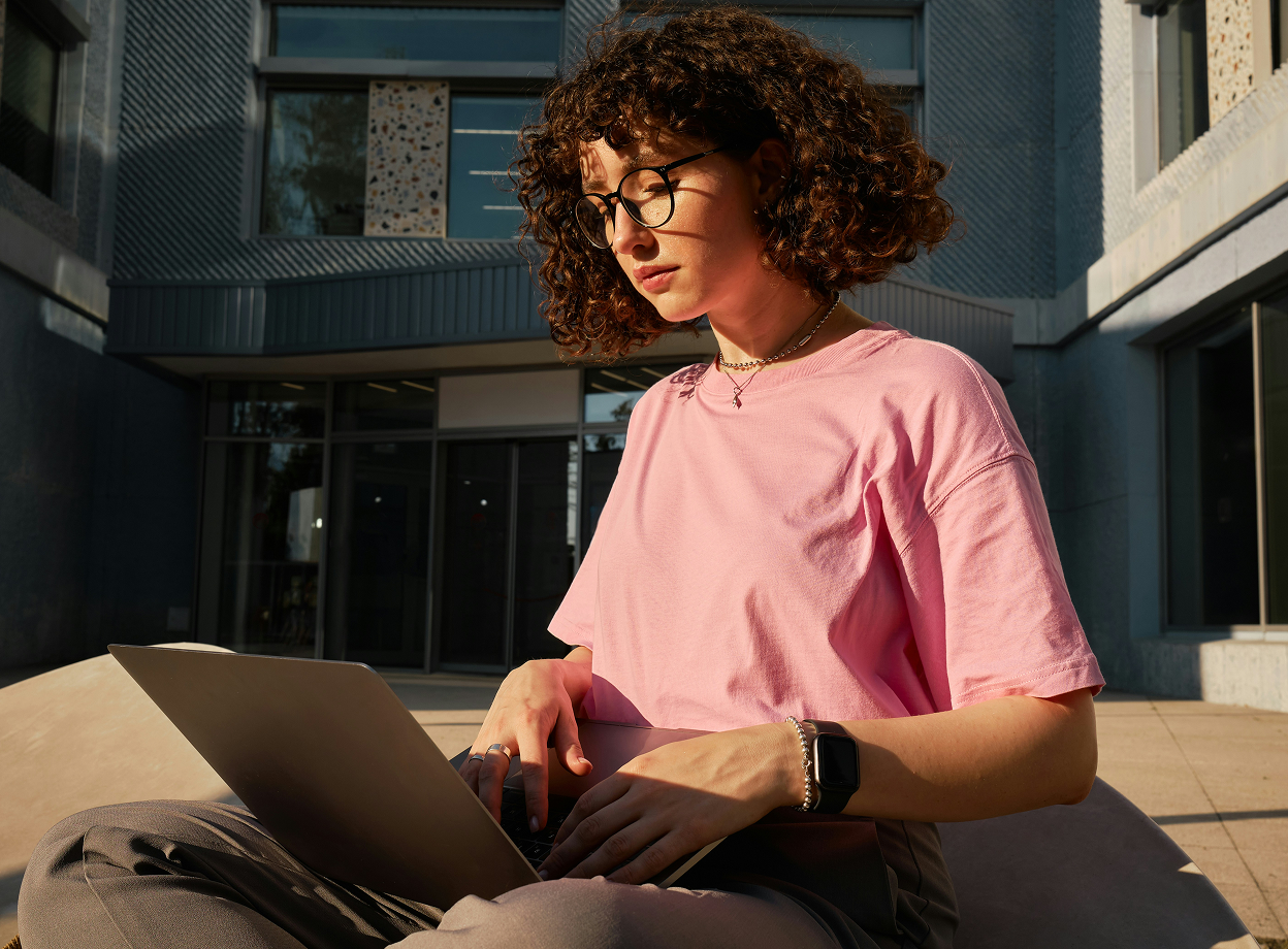 Person sitzt mit Laptop im Freien und arbeitet digital an Dokumenten zur elektronischen Unterschrift.