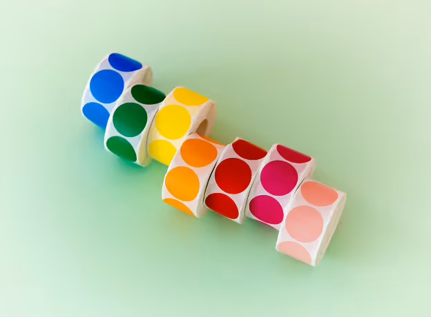 Bunte Aufkleber-Rollen in verschiedenen Farben symbolisieren die strukturierte Ressourcenplanung bei Parallelprojekten.