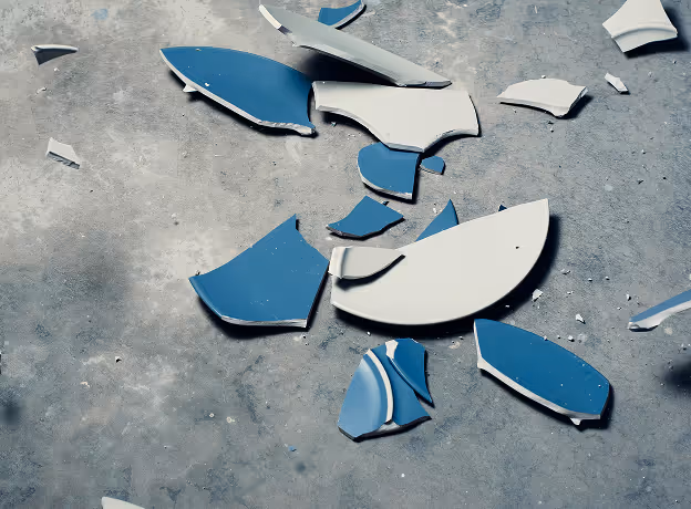 Zerbrochene blaue Keramikscherben auf grauem Betonboden symbolisieren das Scheitern strategischer Projekte durch fehlende Struktur.