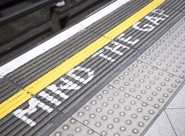 Bahnsteigkante mit gelbem Warnstreifen und Mind-the-Gap-Schriftzug – Symbol für die Lücke zwischen Planung und Realität im Projektcontrolling.