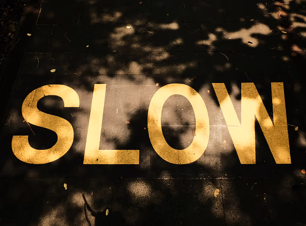 Goldener Schriftzug SLOW auf dunklem Asphalt – PSA-Software beschleunigt Projektgeschäft, das Excel ausbremst.