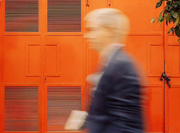 Person in Bewegungsunschärfe vor roter Industrietür – symbolisiert den dynamischen Umgang mit Änderungen im Projektverlauf.