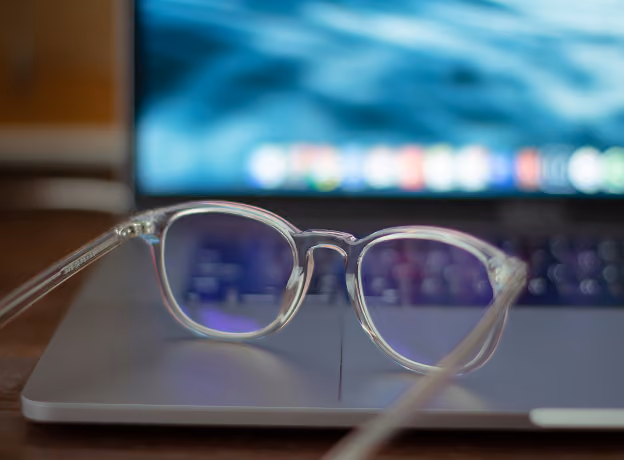 Brille auf Laptop-Tastatur mit Datenanzeige im Hintergrund für datenbasierte Projektsteuerung
