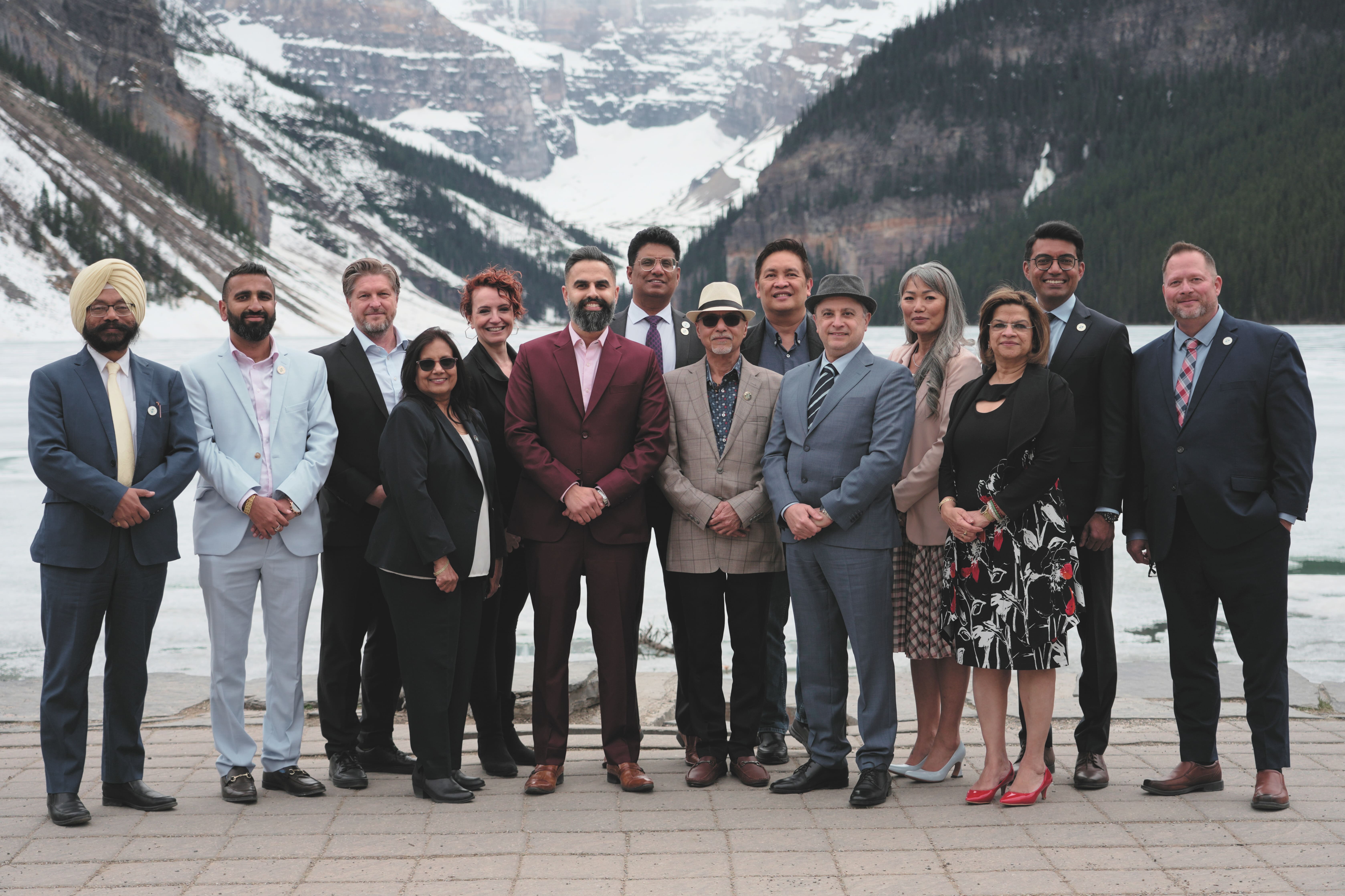 Photo of Dory Jade standing with a diverse group of immigration professionals in front of a mountain lake.
