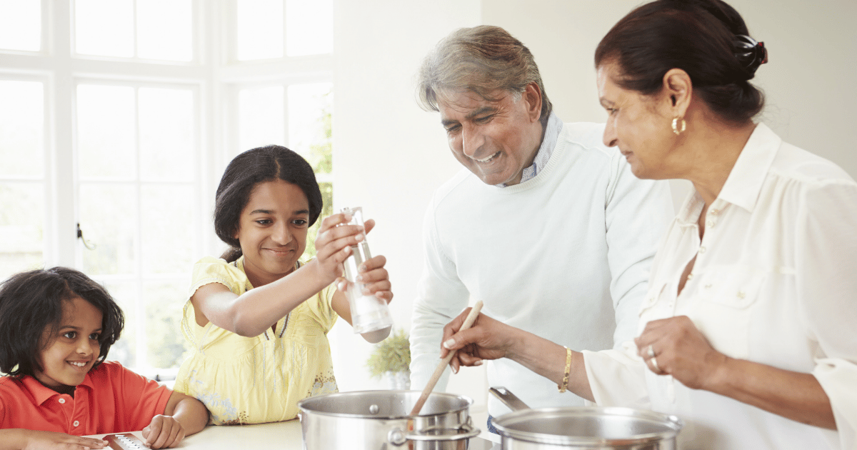 Grandparents shown in the kitchen cooking with grand children