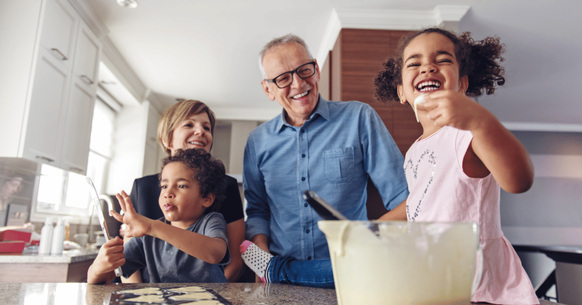 A young girl tasting cake batter with her grandparents
