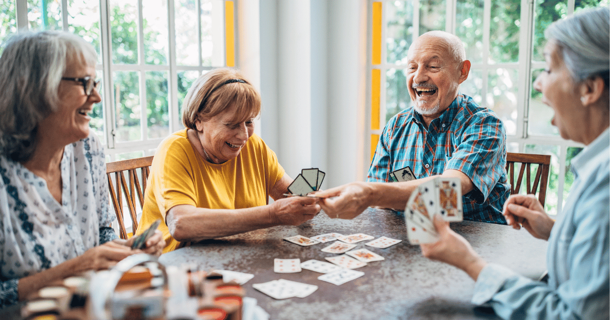 A group of older people playing cards and smiling