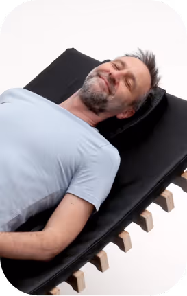 Älterer Mann entspannt lächelnd auf relounge Regenerationsliege – smarte EMS-Erholung für jedes Alter mit moderner Technologie.