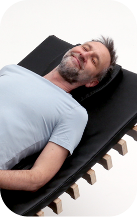 Älterer Mann entspannt lächelnd auf relounge Regenerationsliege – smarte EMS-Erholung für jedes Alter mit moderner Technologie.