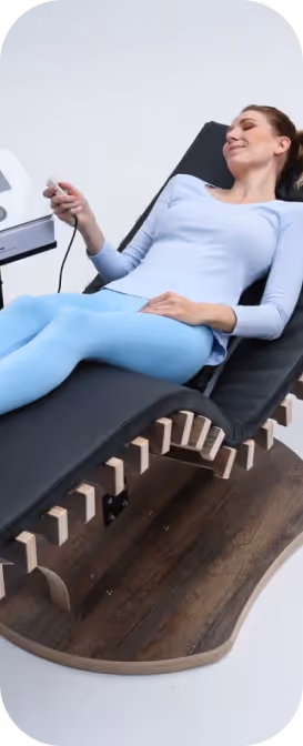 Frau auf relounge Regenerationsliege mit Fernbedienung – benutzerfreundliche EMS-Wellness für Muskelregeneration und smarte Erholung.