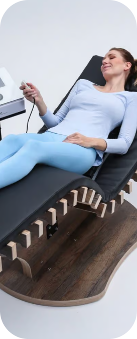 Frau auf relounge Regenerationsliege mit Fernbedienung – benutzerfreundliche EMS-Wellness für Muskelregeneration und smarte Erholung.