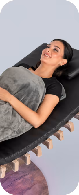 Lächelnde Frau entspannt auf relounge Regenerationsliege mit Decke – smarte EMS-Wellness, Regeneration und ganzheitliche Erholung.