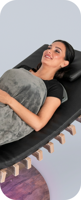 Lächelnde Frau entspannt auf relounge Regenerationsliege mit Decke – smarte EMS-Wellness, Regeneration und ganzheitliche Erholung.