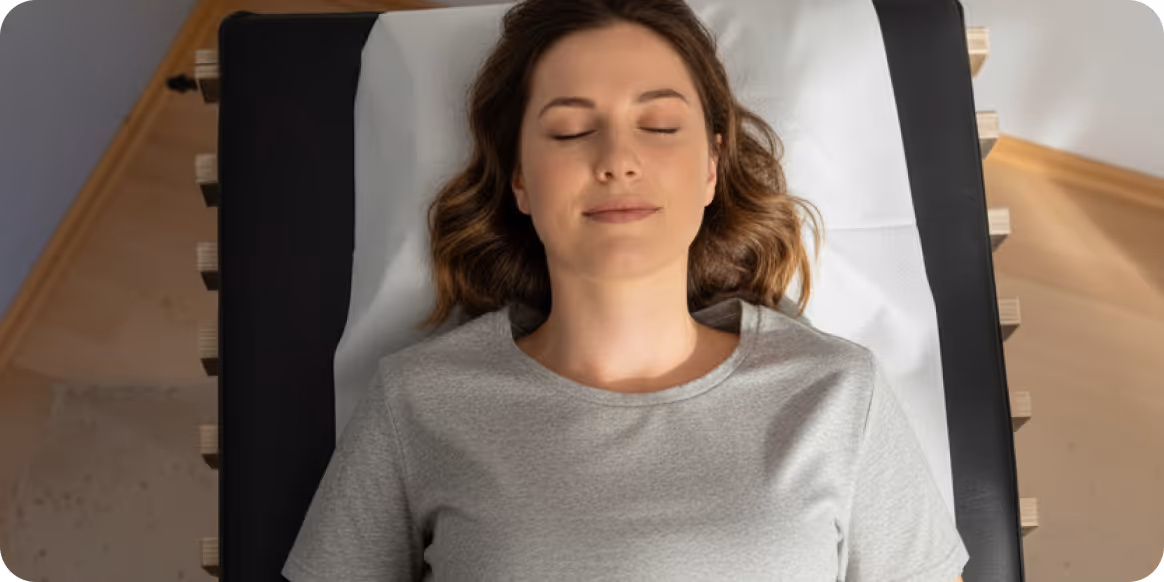 Woman relaxing on a recovery bench after EMS training session with relounge, promoting muscle regeneration, wellness, and smart body recovery.