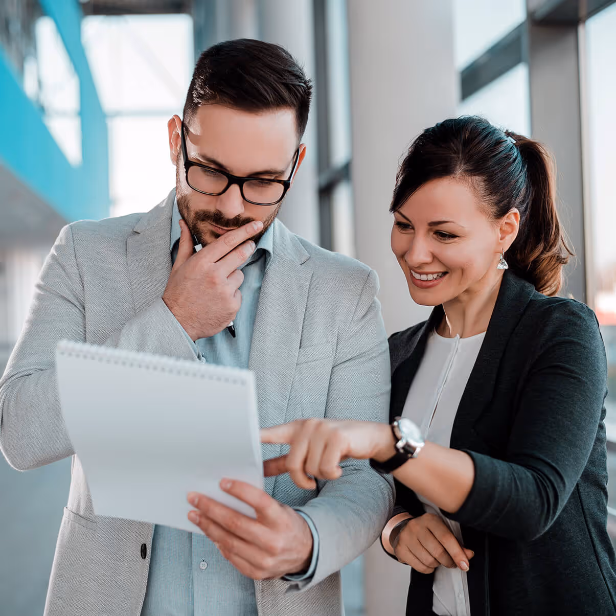 two people standing, looking at a piece of paper