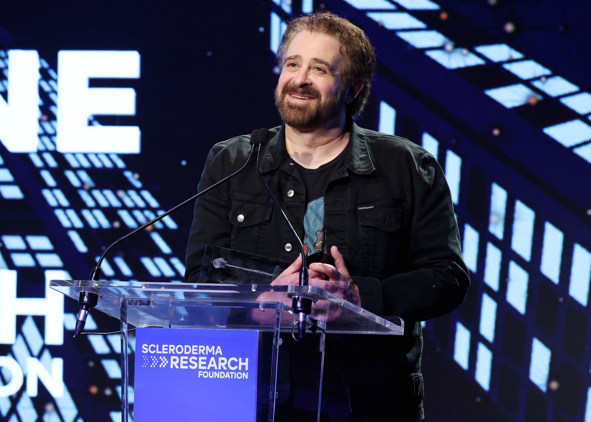 NEW YORK, Nov. 12, 2025 — Adam Duritz speaks onstage during the Scleroderma Research Foundation’s Cool Comedy • Hot Cuisine event at the Edison Ballroom in New York City. (Photo by Kevin Mazur/Getty Images for the Scleroderma Research Foundation) / Source: Scleroderma Research Foundation (SRF) (EZ Newswire)