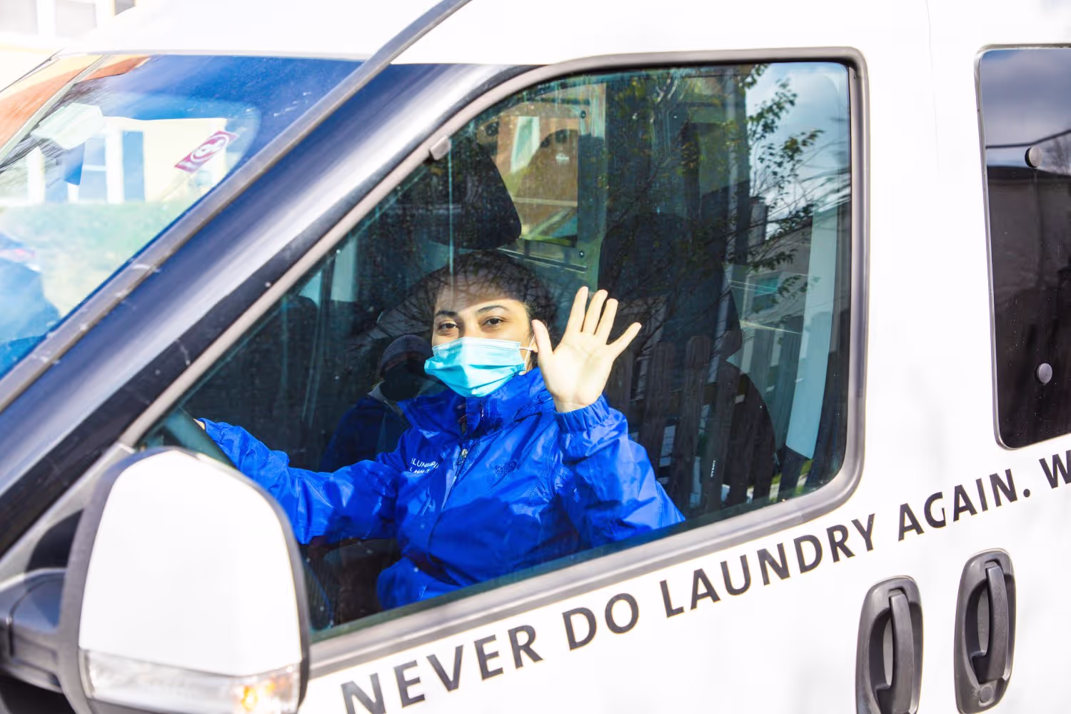 One of our delivery drivers waving to a customer after making a laundry delivery
