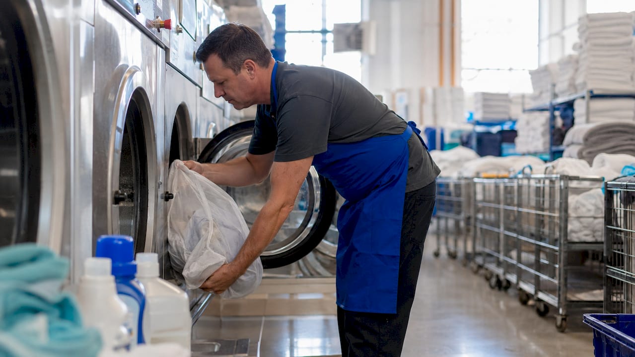 Technician loading commercial washers at facility