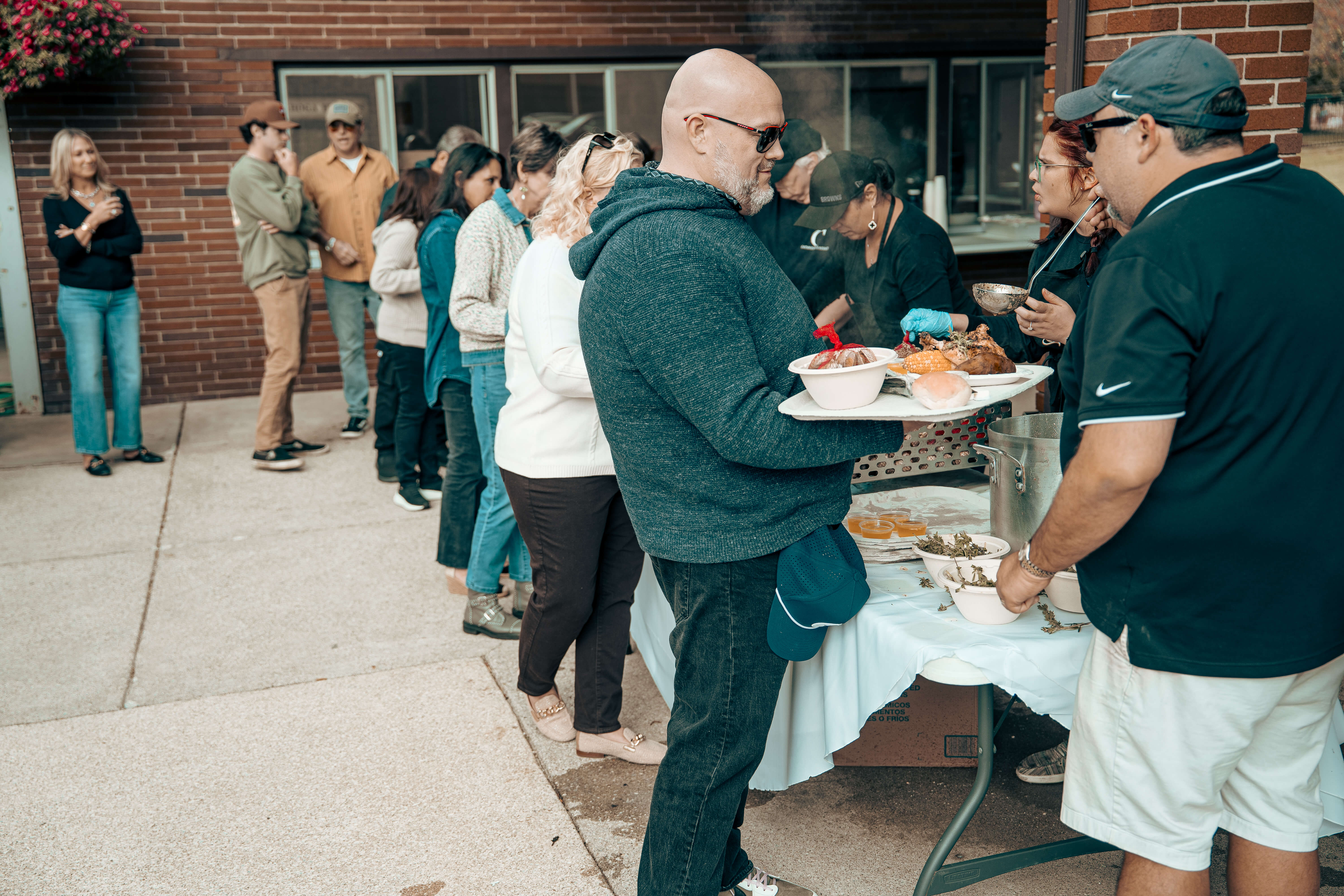 People waiting in line for food at an outdoor buffet table