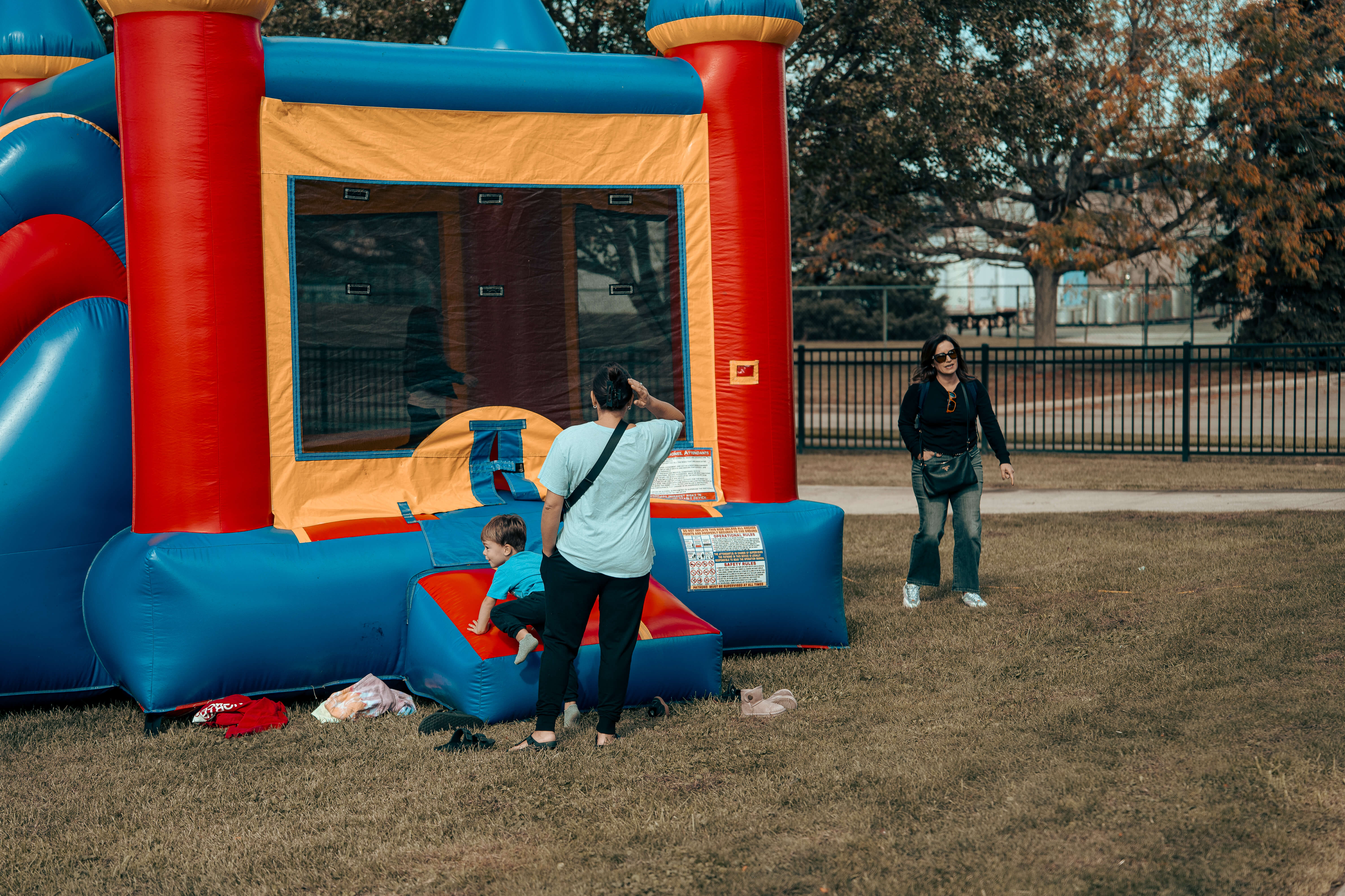 Colorful bounce house with child and adult on grassy field
