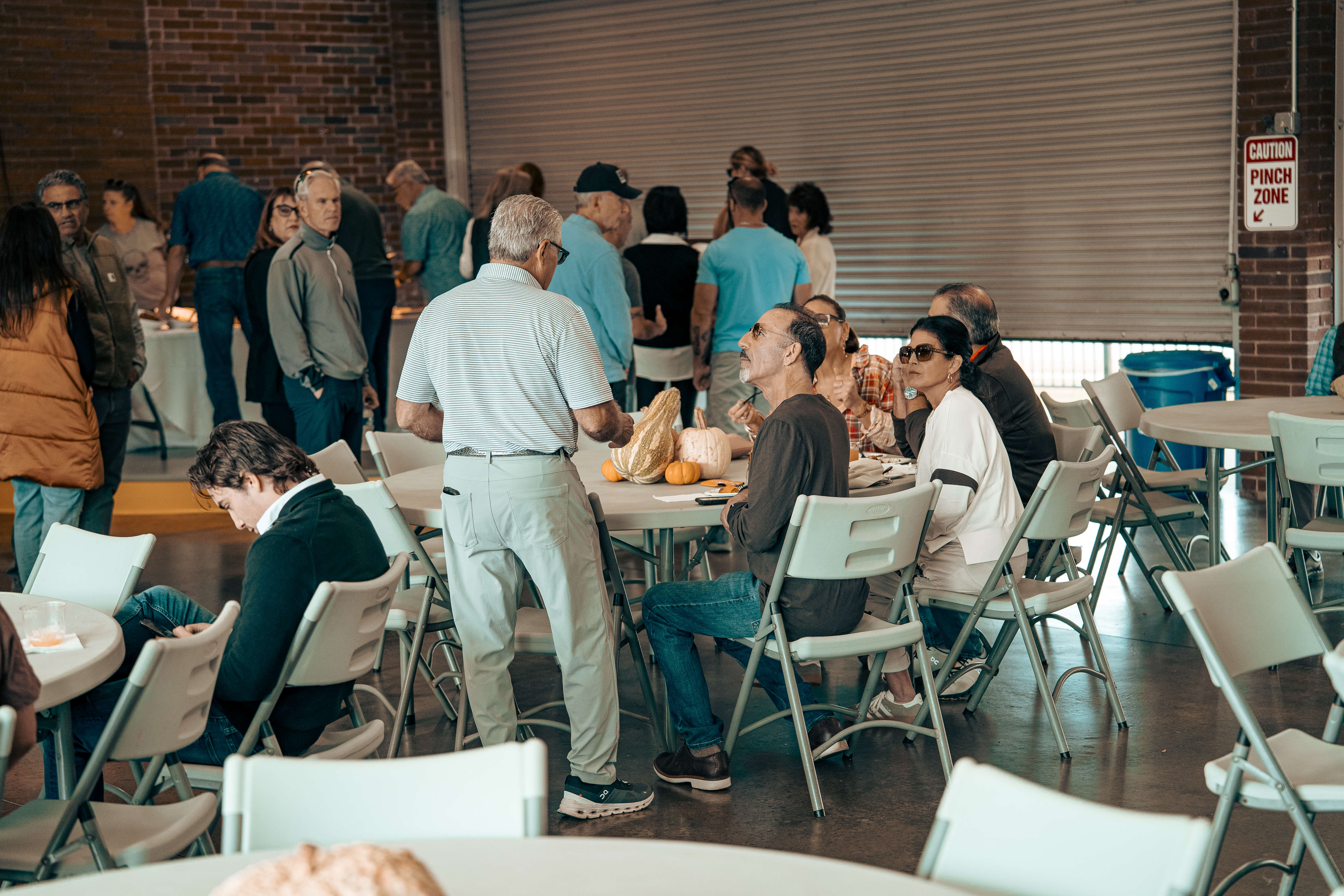 Community gathering with people sitting and standing at folding tables