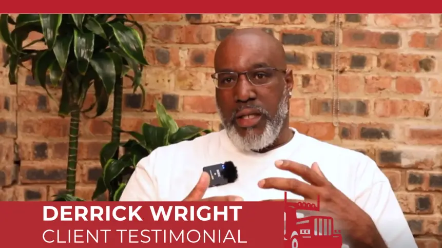 Derrick Wright giving a client testimonial video interview, framed by a brick wall and a tall plant. 
