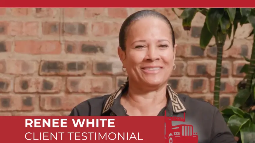 Renee White, a client, smiles genuinely while giving her testimonial in this video screenshot. She is positioned against a warm brick background, conveying confidence and satisfaction with the service she received.