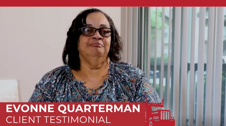 Evonne Quarterman, a client, shares her positive testimonial in this video screenshot. She is wearing glasses and a patterned top, conveying a friendly and approachable demeanor. 