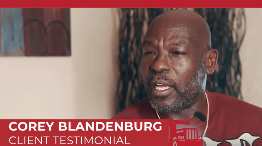 Corey Blandenburg giving a client testimonial video interview, wearing a red shirt. 