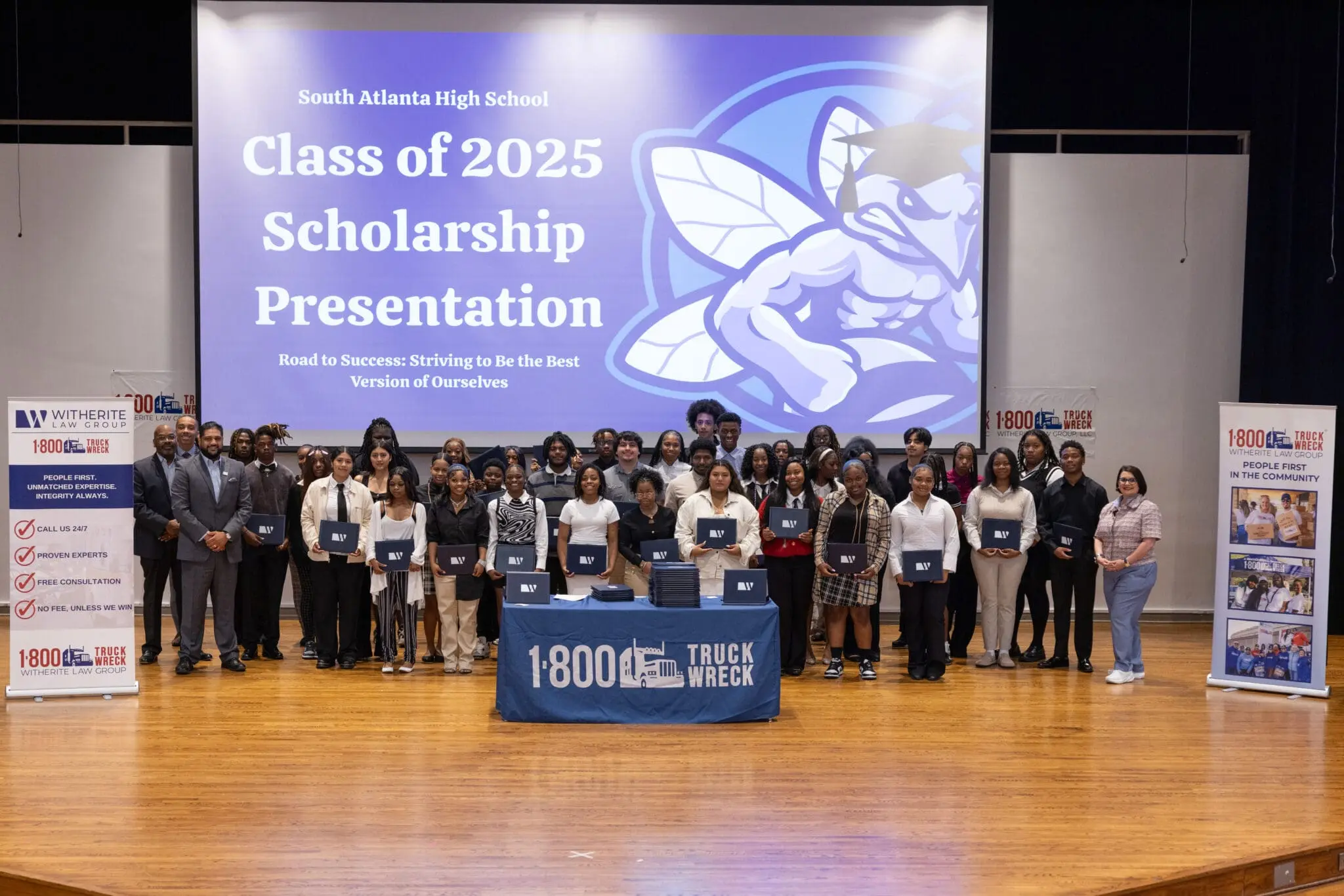 Group photo on a stage during the South Atlanta High School Class of 2025 Scholarship Presentation. Students are holding their certificates in front of a screen displaying the event title.