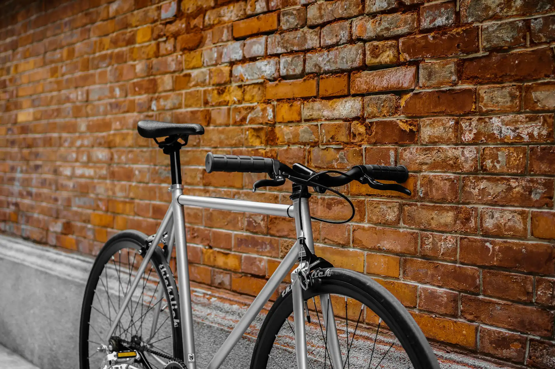 Bicycle leaning against red brick wall