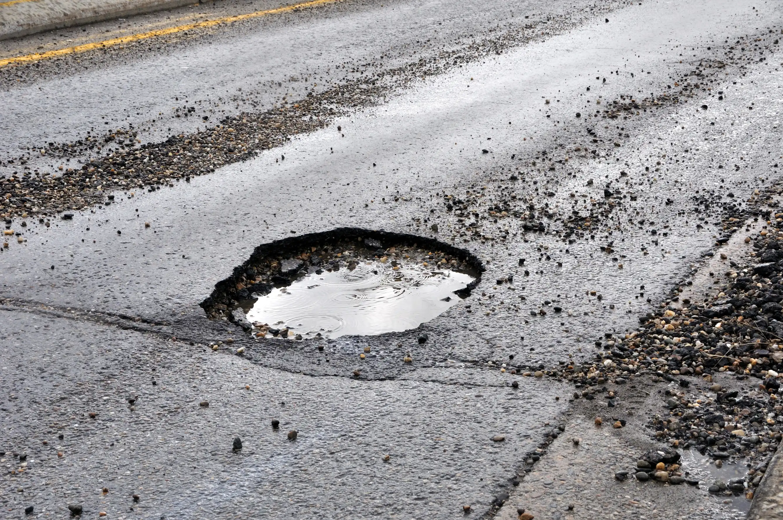 Dangerous roadway with pothole and asphalt debris