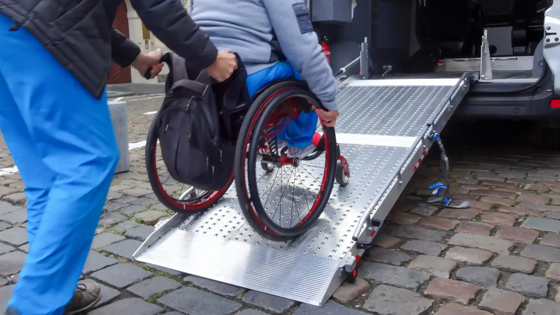 Attendant wheeling person with spine injury into modified van