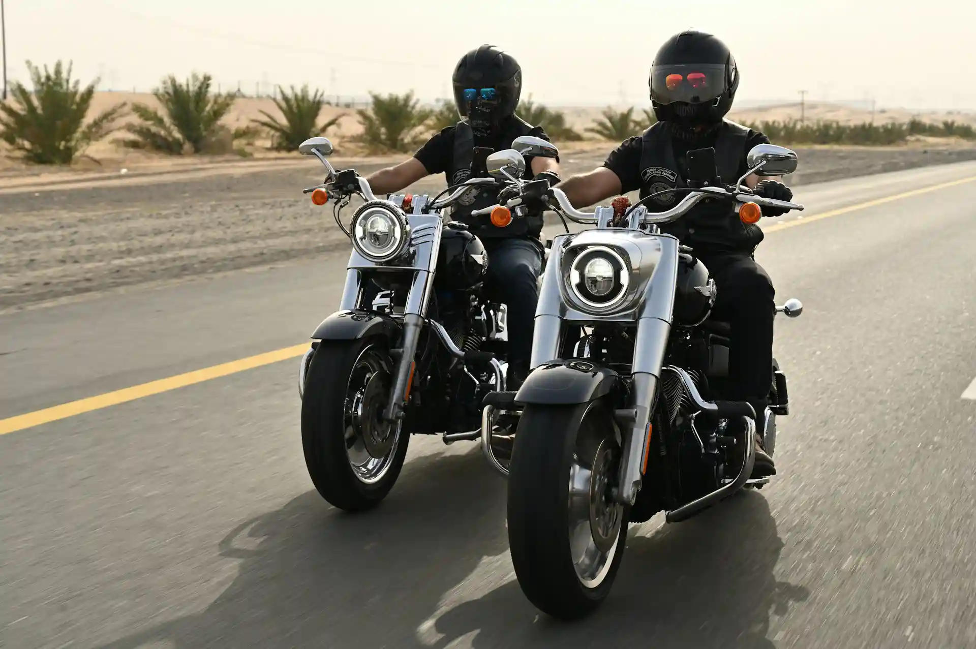 Two motorcycle riders wearing DOT-approved helmets riding on a San Diego highway
