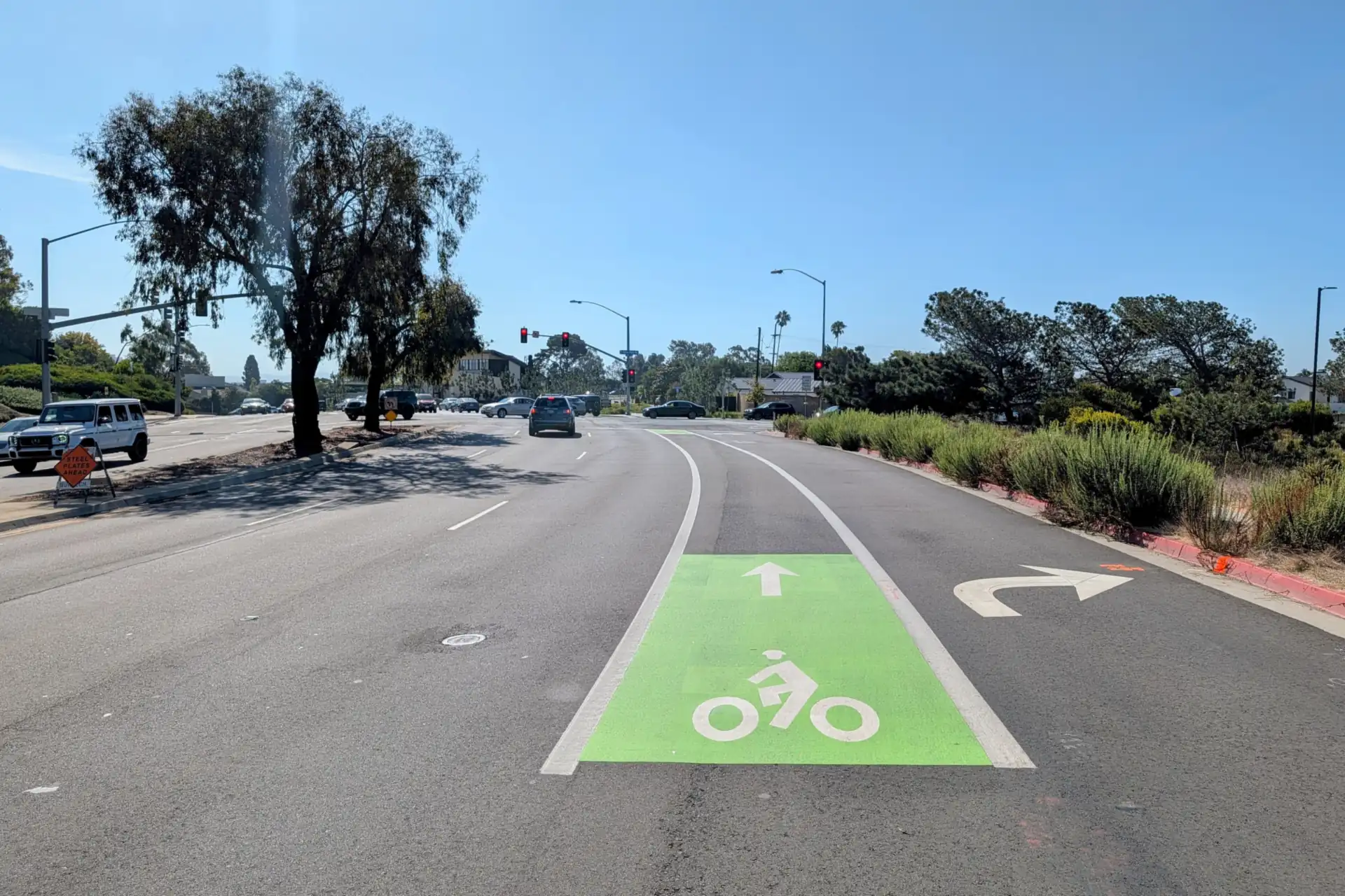 Newly painted green bike lane and fresh white lane striping approaching a signalized intersection on a San Diego road.