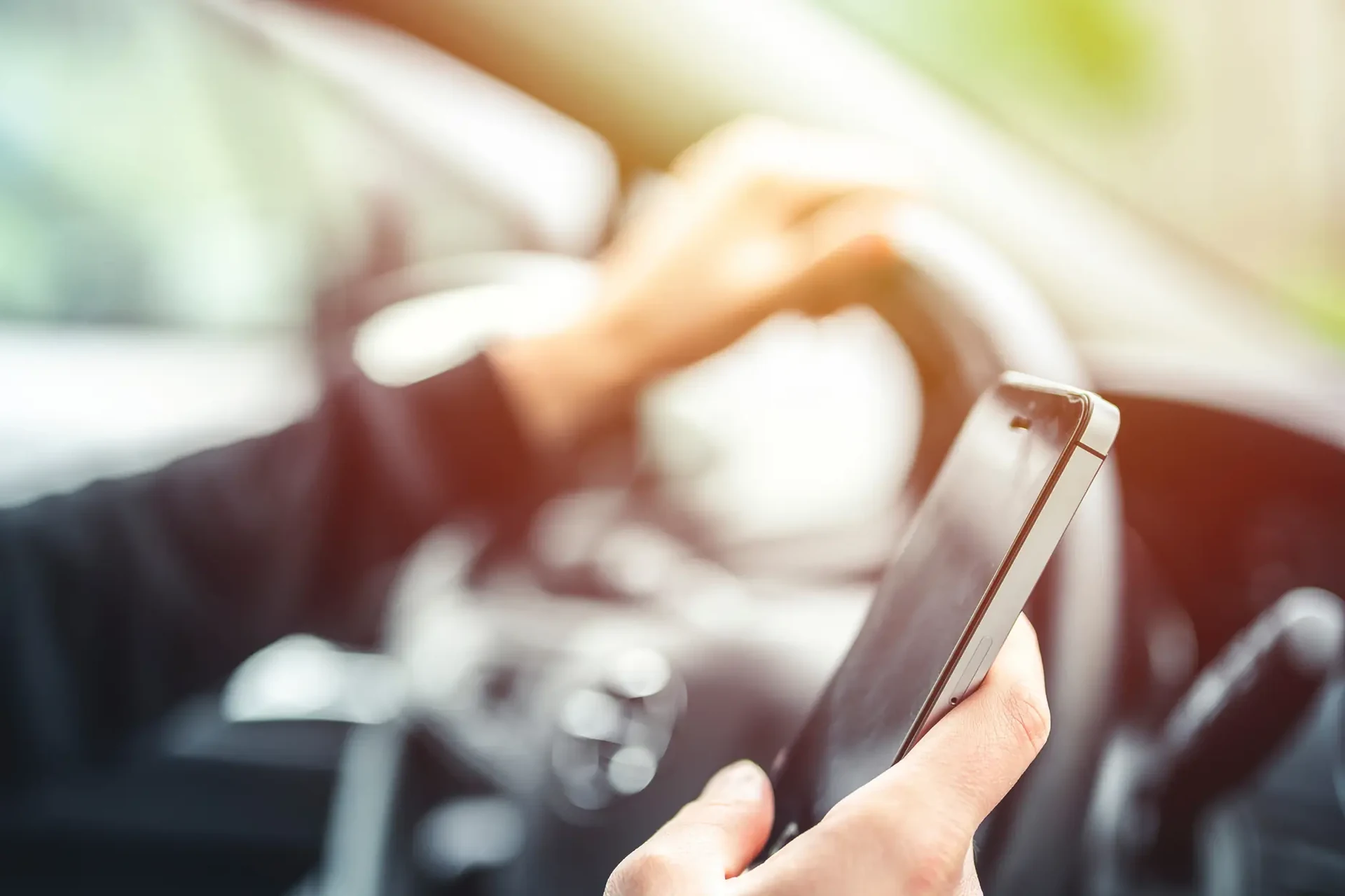A distracted driver holding a cell phone in one hand while steering with the other.