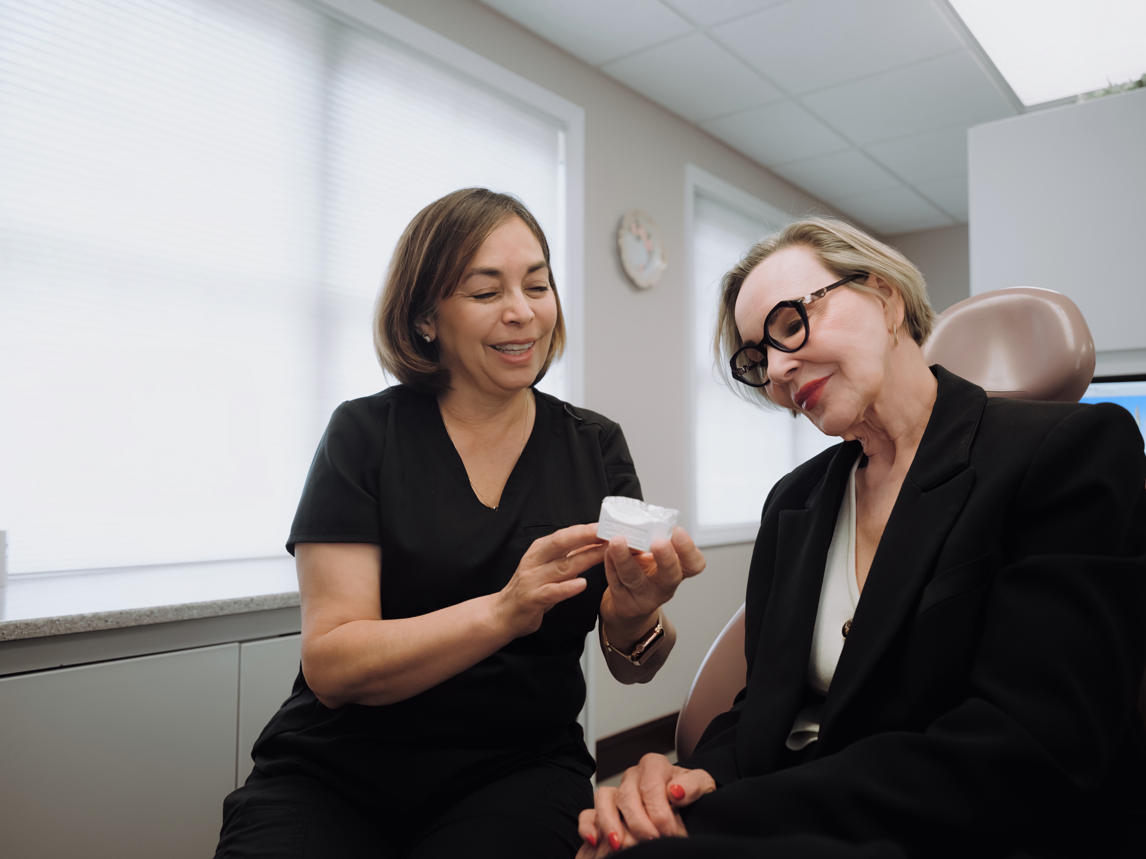 Dentist showing dental patient a mold of her mouth to explain crown process.