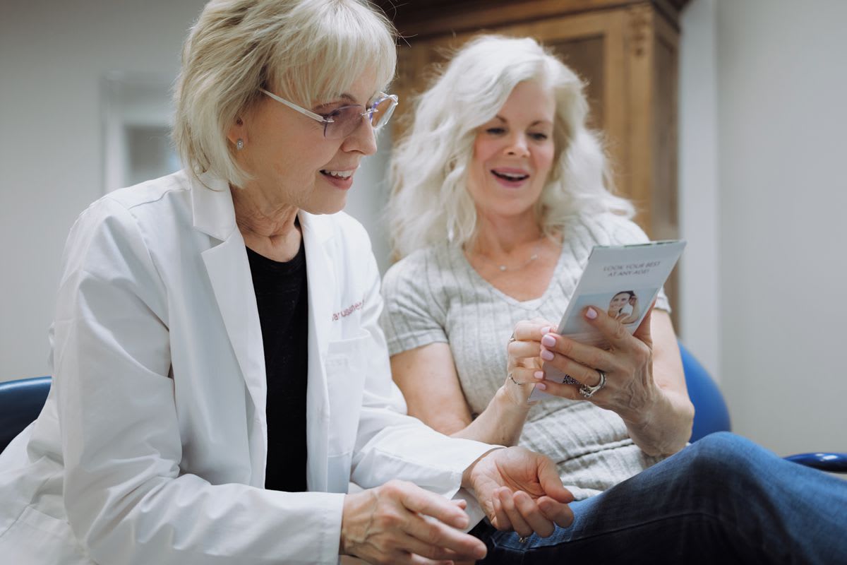 Two women reviewing dental treatment options on a tablet in a dental office consultation room.