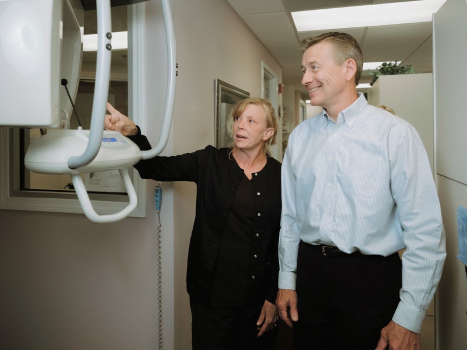 Dr. Barbara Preussner and a male colleague examine dental equipment in a clinical treatment room.
