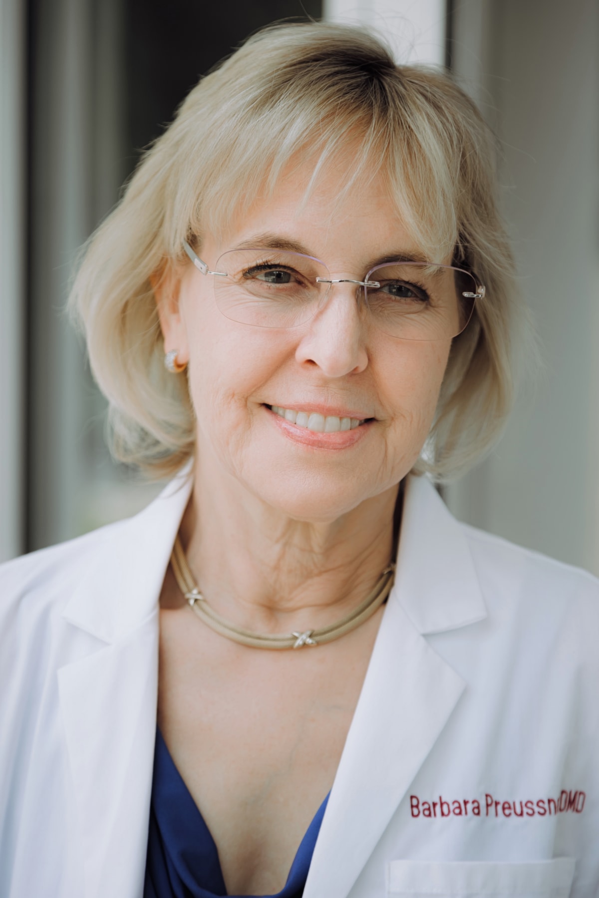 Barbara Preussner DMD portrait in professional white coat and glasses